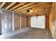 Garage under construction with white door, concrete floor and framed unfinished walls at 2013 Yandes St, Indianapolis, IN 46202