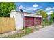 View of the garage with a basketball hoop with a weathered red door and partial wooden fence at 207 S Center St, Plainfield, IN 46168