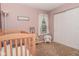 Charming bedroom with light pink walls, crib, white wicker chair, and bright window at 270 Rapid Rill Ln, Brownsburg, IN 46112