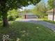 Two-car detached garage with red entry door and driveway and a yard with large tree at 3528 Orchard Ave, Indianapolis, IN 46218