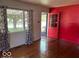 Inviting living room with a vibrant red accent wall and sun-drenched hardwood floors at 3528 Orchard Ave, Indianapolis, IN 46218