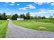Gravel driveway leading to a charming home and garage, surrounded by green lawns at 3682 S 380 E, Anderson, IN 46017