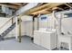 Bright basement laundry area featuring a washer, dryer, utility sink, and accessible stairs at 4447 N College Ave, Indianapolis, IN 46205