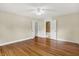 Spacious bedroom with hardwood floors, neutral paint, and white trim, offering access to the hallway and bathroom at 4447 N College Ave, Indianapolis, IN 46205