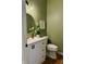 Charming powder room features green walls, sleek vanity with a round mirror, and modern fixtures at 4601 Fairhope Dr, Indianapolis, IN 46237