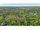 A serene aerial view showcases a neighborhood with mature trees, green spaces, and various home styles under a blue sky at 5783 Coopers Hawk Dr, Carmel, IN 46033