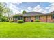 Well-maintained backyard features lush green grass, mature trees, and a brick home exterior at 6005 Apache Dr, Indianapolis, IN 46254