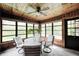 Sunroom featuring bright windows, wood paneling and white patio chairs at 6005 Apache Dr, Indianapolis, IN 46254