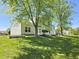 Scenic backyard featuring a lush lawn, mature trees, white exterior of the home, and a deck at 6369 Kelsey Dr, Indianapolis, IN 46268