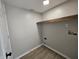 Dedicated laundry room space with wood shelf, hook ups, luxury vinyl plank flooring, and neutral paint at 6369 Kelsey Dr, Indianapolis, IN 46268