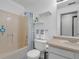 Bright bathroom showcasing a shower-tub combination, toilet, vanity with sink, and decorative shelves at 6707 Greendale Ln, Indianapolis, IN 46241