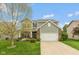 Charming two-story home featuring gray siding, a brick accent, a well-manicured lawn, and an attached two-car garage at 695 Bobtail Dr, Greenfield, IN 46140