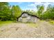 Exterior of a large, rustic barn with a gravel base and verdant trees, set against a blue sky at 6968 S 300 W, Trafalgar, IN 46181