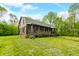 Classic log cabin with a covered porch, lush lawn, mature trees, and inviting curb appeal in a tranquil, wooded setting at 6968 S 300 W, Trafalgar, IN 46181
