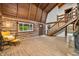 Spacious living room with a cozy yellow chair, log walls, wood floors, and staircase at 6968 S 300 W, Trafalgar, IN 46181