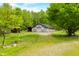 A large, rustic barn on a lush green lawn with a gravel driveway and mature trees at 6968 S 300 W, Trafalgar, IN 46181