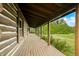 Covered porch with wood flooring, offering a relaxing outdoor space with views of the lush landscape at 6968 S 300 W, Trafalgar, IN 46181