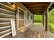Inviting covered porch of log cabin with 'welcome' decor, a swing, and a view of the serene, wooded surroundings at 6968 S 300 W, Trafalgar, IN 46181