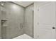 Sleek bathroom shower with glass door and tiled surround next to a white door at 7132 Sterling Way, Brownsburg, IN 46112