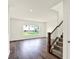 Open living room showcasing hardwood floors, a staircase, and natural light from the window at 7132 Sterling Way, Brownsburg, IN 46112