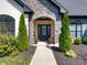 Charming stone archway frames the entry, flanked by manicured shrubbery and a black front door with glass inserts at 8112 Joni Ave, Martinsville, IN 46151