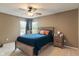 Comfortable bedroom with a wooden frame bed, matching nightstand, ceiling fan, and natural lighting at 828 Breaside Ln, Greenwood, IN 46143