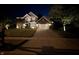 Charming two-story brick home featuring manicured lawn, well-lit driveway, and inviting curb appeal at night at 828 Breaside Ln, Greenwood, IN 46143