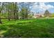Large green backyard with scattered trees, landscaping and a partial view of the exterior of the home at 965 W Main St, Greenwood, IN 46142