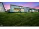 Backyard at dusk featuring a large green lawn and covered back porch with outdoor grill at 9822 Tampico Chase, Fishers, IN 46040