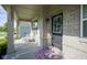 Covered front porch featuring a black door with wreath, cozy wicker seating, and brick columns at 9822 Tampico Chase, Fishers, IN 46040