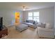 Bright living room with couch, ottoman, carpet, and adjacent laundry room at 10316 Hatherley Way, Fishers, IN 46037