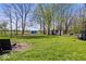 Relaxing backyard view, featuring mature trees, a grassy yard, and a fire pit at 10473 N County Road 950 E, Brownsburg, IN 46112