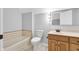 Bright bathroom features a bath tub, white toilet, and vanity with a wood cabinet at 10602 Fall Rd, Fishers, IN 46037
