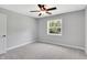 Bright bedroom featuring neutral carpet, ceiling fan, and a window looking out onto greenery at 10602 Fall Rd, Fishers, IN 46037