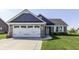 Charming front exterior showcasing a two-car garage, stone accents, and a landscaped yard at 1115 Senate Dr, Edinburgh, IN 46124