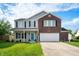 Charming two-story home boasts a well-manicured lawn and an inviting, covered front porch with vibrant flower accents at 1257 Rosemary Ct, Greenfield, IN 46140