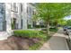Close-up of the condo building featuring bushes, grass, and trees that line the sidewalk at 12833 Tradd St # 1B, Carmel, IN 46032