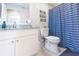 Well-lit bathroom with a vanity, modern sink, toilet, and a blue wave-patterned shower curtain creating a fresh atmosphere at 1472 Maple Ridge Ct, Columbus, IN 47201