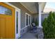 Warm and inviting porch featuring a bright yellow door and cozy seating area at 1472 Maple Ridge Ct, Columbus, IN 47201