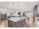 Modern kitchen featuring white cabinets, a spacious island with seating, and a seamless transition to the living room at 15143 Gallop Ln, Fishers, IN 46040
