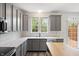 Well-lit kitchen featuring gray cabinets, modern appliances, quartz countertops, and a view to the yard at 16001 Concert Way, Noblesville, IN 46060