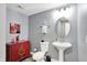 Stylish powder room features a pedestal sink and charming red accent cabinet at 16516 Wilsons Farm Dr, Fishers, IN 46040