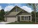 Charming craftsman-style home with green siding, stone accents, covered porch, and attached two-car garage at 2047 Quail W Dr, Danville, IN 46122