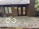Brick home exterior showcasing a walkout patio surrounded by landscaping stones and featuring double glass doors at 209 Brighton Ct, Greenwood, IN 46143