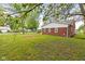 Backyard featuring a brick home, green lawn, and shady trees at 2321 W 26Th St, Anderson, IN 46016