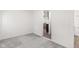 This bedroom is empty with light grey carpet, white walls, and a door to the kitchen at 2321 W 26Th St, Anderson, IN 46016