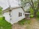 Rear exterior shows white siding, an electrical box, and overgrown landscaping at 29 E Pine St, Anderson, IN 46012