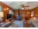 Warm living room with wood paneled walls, a ceiling fan, fireplace, and cozy seating at 295 Maple Turn Rd, Martinsville, IN 46151
