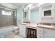 Bright bathroom with dual vanities, wood stool, a shower-tub combo, and blue bath mats at 3022 Cameron St, Indianapolis, IN 46203