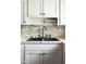 Close up of kitchen sink with white cabinets and stone backsplash at 3022 Cameron St, Indianapolis, IN 46203